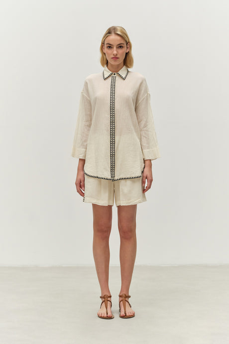 Off-white long-sleeve shirt with black contrast piping paired with matching shorts.