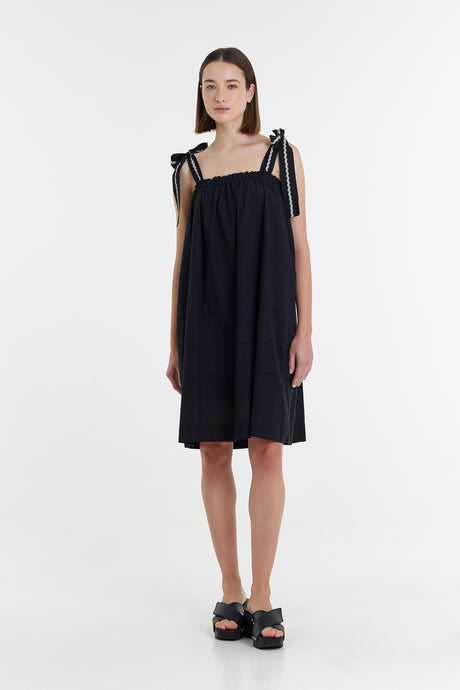 Black sleeveless short dress with tied shoulder straps and loose A-line silhouette.