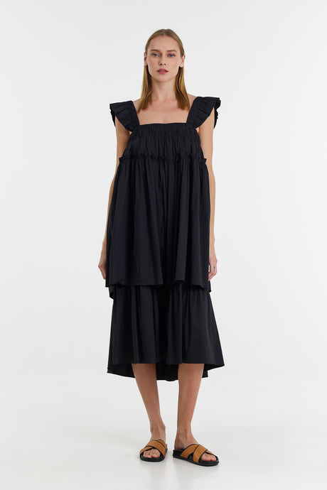 Black midi dress with ruffled cap sleeves and tiered skirt, styled with flat sandals.