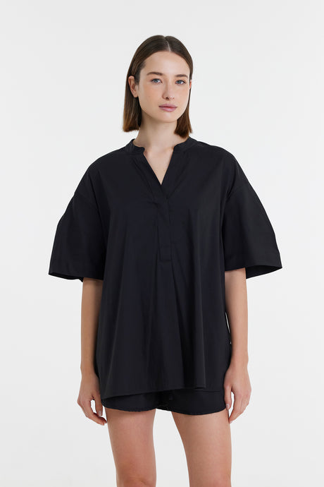 Black short-sleeve blouse with a V-neck and relaxed fit on model.