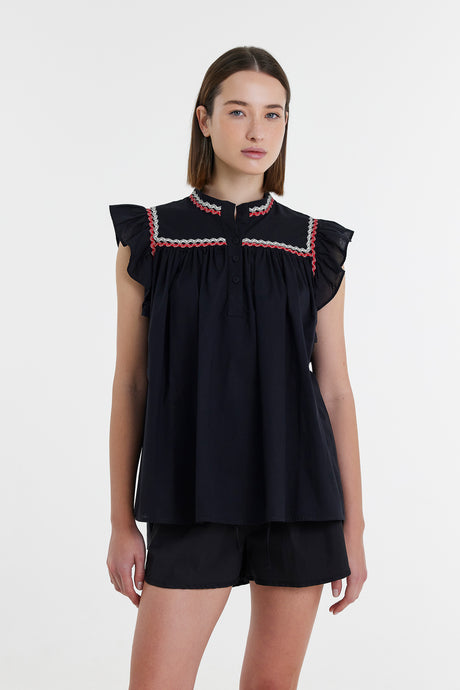 Black sleeveless blouse with ruffled shoulders and red-white embroidered trim on yoke.