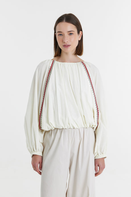 Offwhite long-sleeve blouse with gathered waist and red trim detail on shoulders.