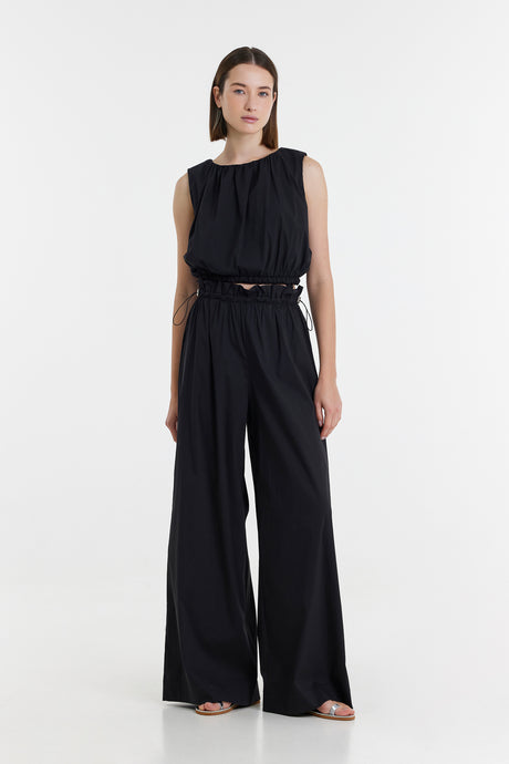 Black sleeveless top with gathered neckline paired with high-waisted wide-leg black pants.