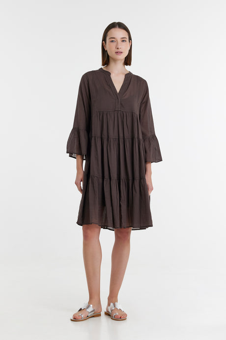 Brown midi dress with tiered skirt, long sleeves, and V-neck collar modeled with sandals.