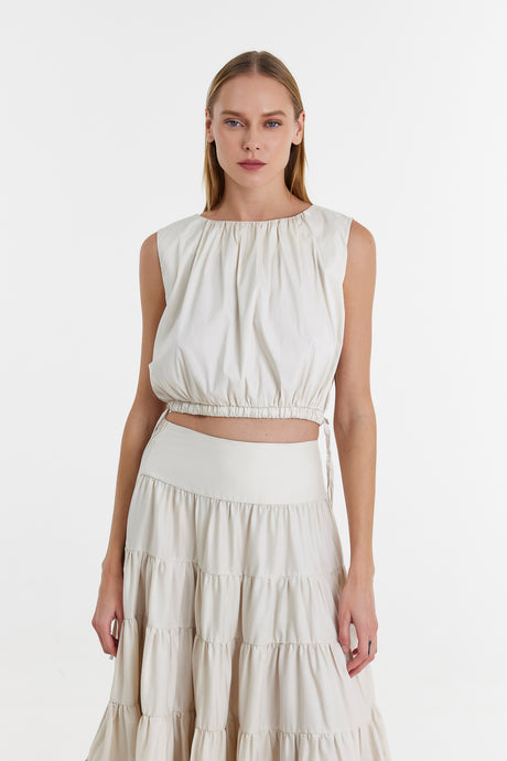Off-white sleeveless blouse with gathered neckline and cropped elastic hem.