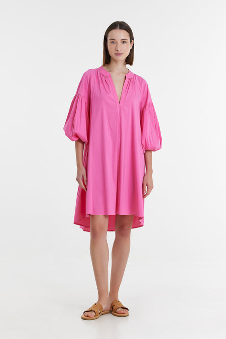 Fuchsia midi dress with voluminous three-quarter sleeves and V-neck collar worn with tan sandals.