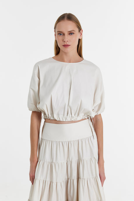 Off-white blouse with puff sleeves and gathered waist paired with tiered skirt.