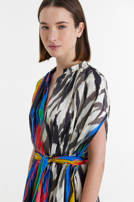 Long dress with multicolor vertical stripes and abstract black-and-white prints, cinched at the waist with a matching belt.