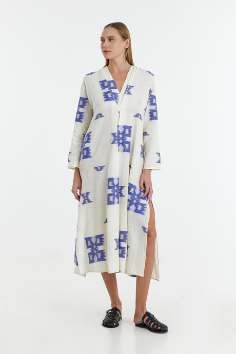 White long jacquard dress with blue geometric print, V-neck, slit, and cuffed sleeves.