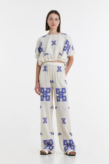 Beige jacquard pants and matching short-sleeve top with blue geometric patterns, relaxed fit.
