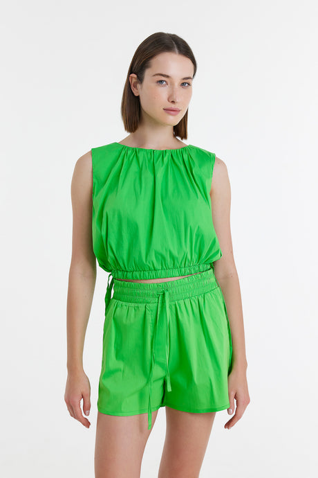 Bright green sleeveless blouse with gathered neckline paired with matching high-waisted shorts.