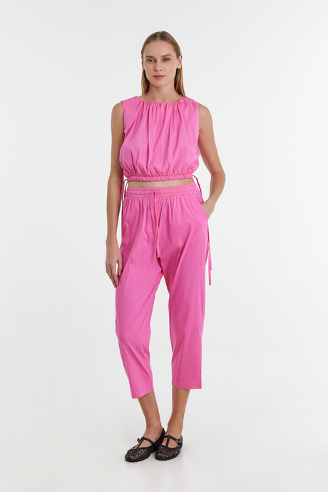 Bright fuchsia sleeveless top with matching high-waist cropped pants and belt details.