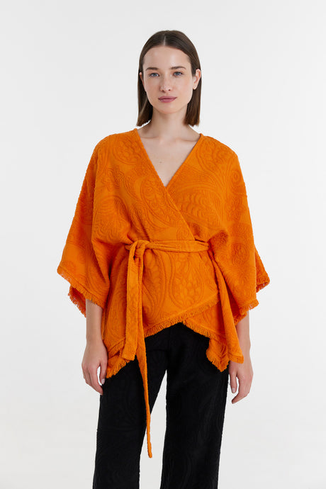 Orange kimono-style blouse with wide sleeves and waist tie, worn with black pants.