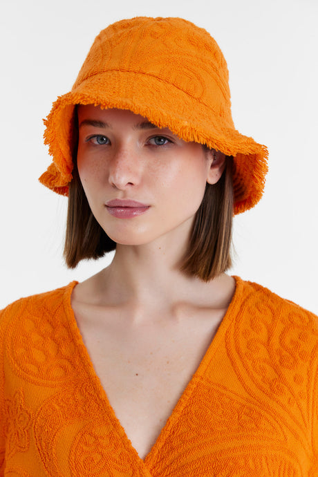 Orange terry cloth bucket hat with textured pattern worn by model.
