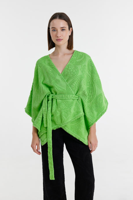Green kimono-style blouse with wide sleeves and a waist tie, worn with black pants.