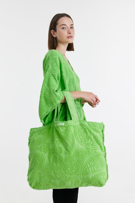 Large green tote bag with textured leaf pattern and wide handles, carried over shoulder.