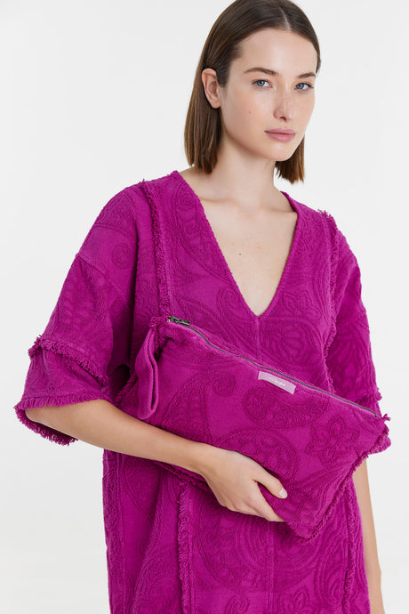 Magenta textured fabric pouch with zipper held by woman wearing matching deep V-neck top.