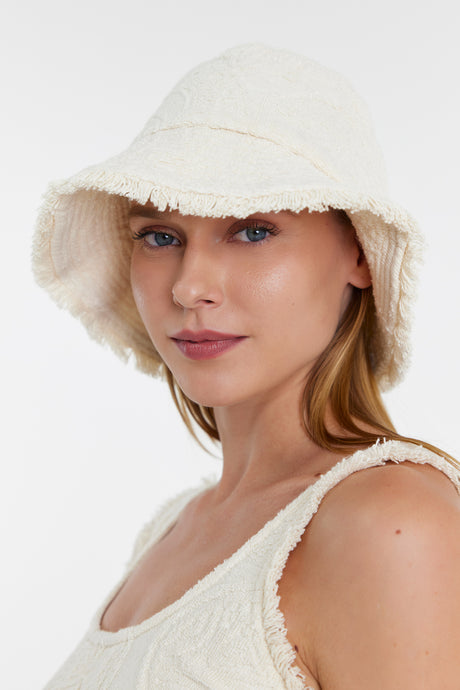 Off-white textured bucket hat with frayed edges worn by woman with matching textured tank top.