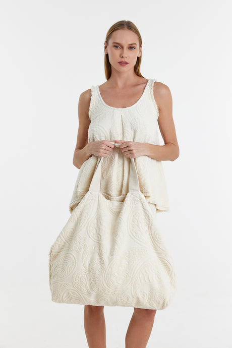 Off-white quilted tote bag with soft fabric and large handles held by model.