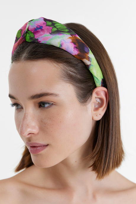 Fuchsia floral fabric hairband with twisted knot detail worn on straight brown hair.