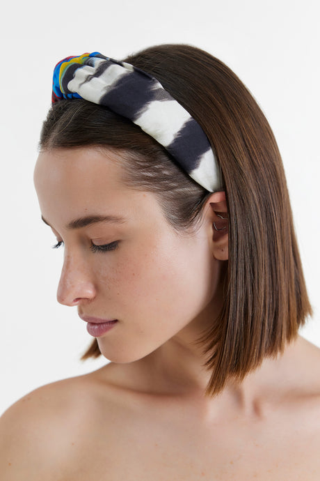 Red padded hairband with twisted knot detail worn on brown shoulder-length hair.