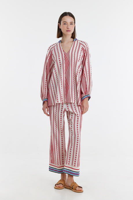 Red and off-white jacquard blouse and wide-leg pants set with blue striped cuffs and hem.