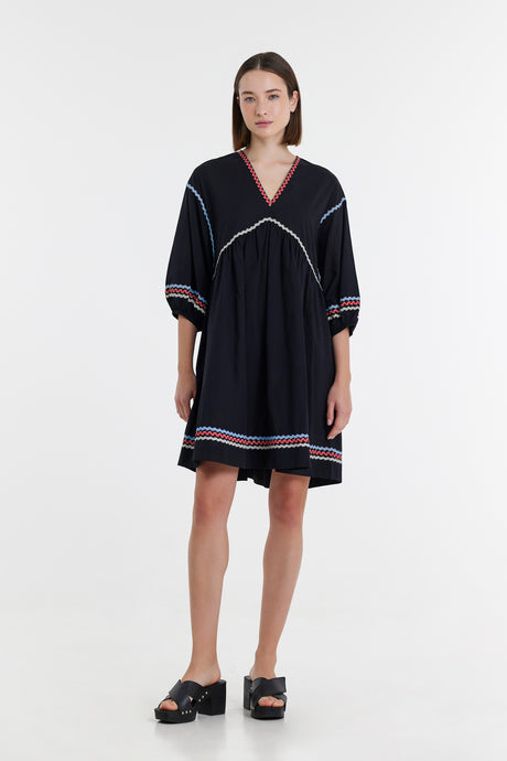 Black short dress with red and white trim, V-neckline, and puffed three-quarter sleeves.