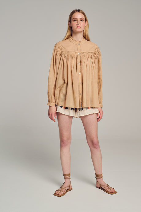 Beige long-sleeve blouse with intricate embroidery and loose fit on model.