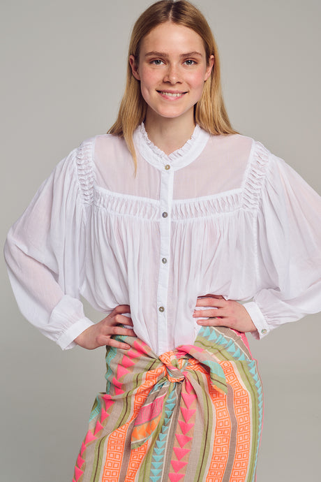 White blouse with billowy long sleeves, pleated front, and button-down closure.