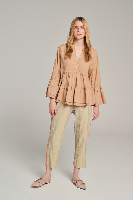 Beige long-sleeve blouse with V-neck and gathered waist, loose fit on model.