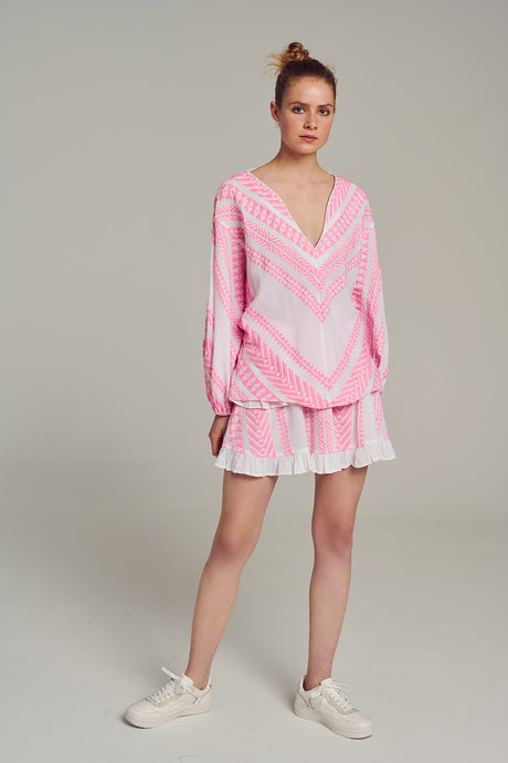 Pink jacquard blouse with long sleeves and V-neck, paired with matching ruffled mini skirt.