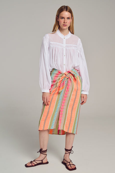 Multicolor striped jacquard midi skirt with front knot detail worn with white blouse and lace-up sandals.