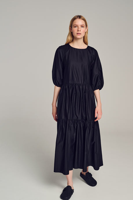 Black long popeline dress with puffed elbow-length sleeves and tiered skirt.