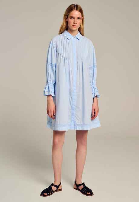Light blue striped shirt dress with long sleeves and button-down front worn with black sandals.