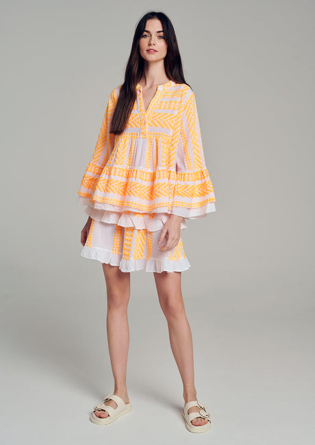 Orange tiered jacquard skirt with ruffled hem, worn with matching loose blouse and sandals.