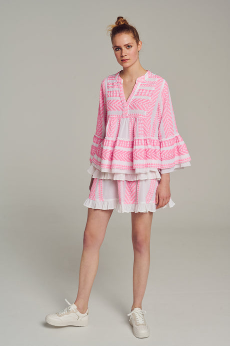 Pink jacquard tiered mini skirt with ruffled hem worn with matching flowy blouse and white sneakers.