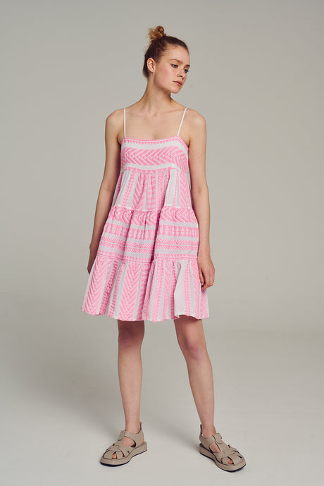 Pink sleeveless jacquard dress with tiered skirt and thin straps worn with sandals.