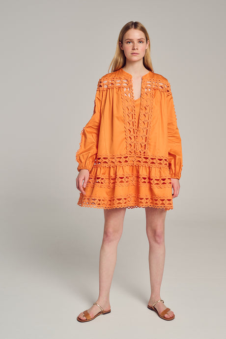 Orange long-sleeve short dress with lace cutouts and tiered skirt in lightweight fabric.