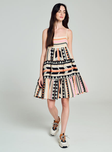 Sleeveless multicolor jacquard dress with geometric patterns and flared skirt worn with sneakers.