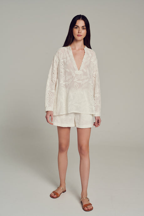 White embroidered lightweight shorts paired with matching wrap-style top and brown slide sandals.