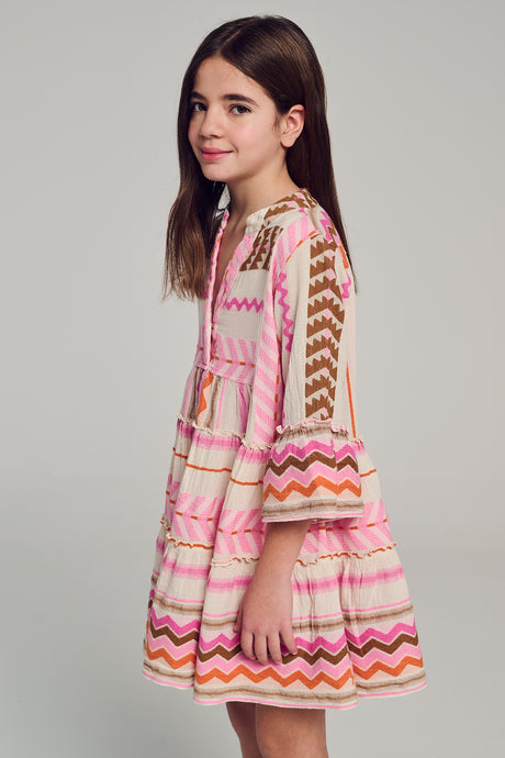 Pink long-sleeve dress with zigzag and chevron patterns and tiered skirt on girl model.