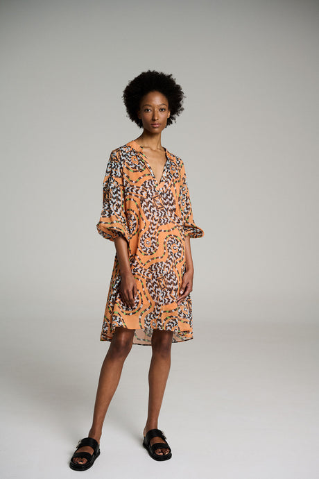 Orange short dress with bold black floral print and loose three-quarter sleeves.