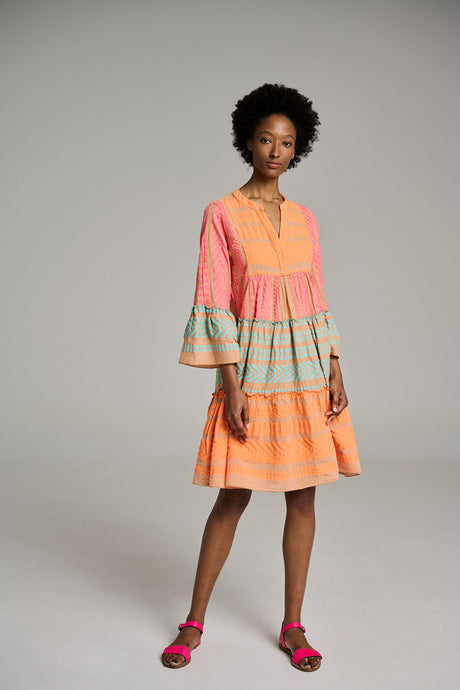 Midi dress with pink, navy, and blue jacquard stripes, V-neck, and tiered skirt, worn with pink sandals.