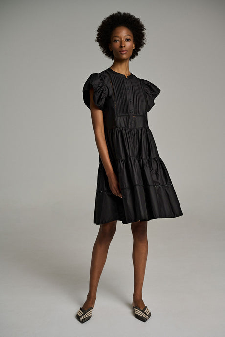 Black short dress with tiered skirt and puffed sleeves, styled with pointed-toe flats.