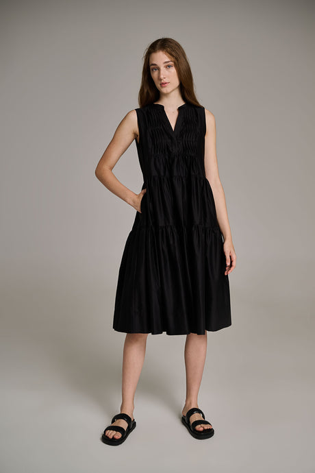 Sleeveless black midi dress with a gathered waist and V-neck collar, worn with black sandals.