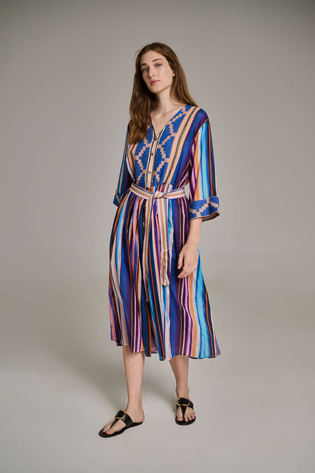 Long blue dress with vertical purple and white stripes, V-neck, and 3/4 sleeves worn with black sandals.