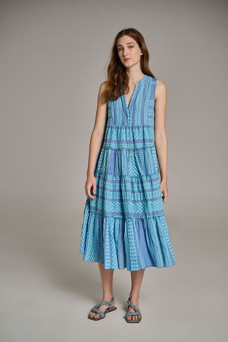 Sleeveless blue jacquard midi dress with V-neck and tiered skirt worn with sandals.
