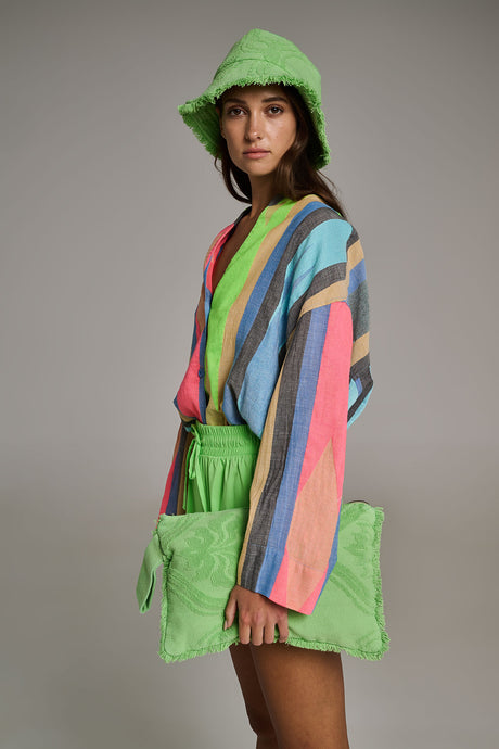 Woman wearing green terry hooded hat and holding matching green terry clutch bag with colorful striped sweater.