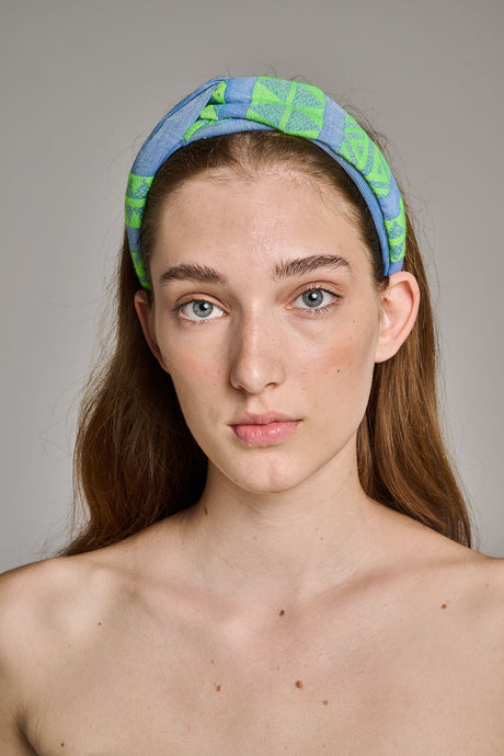 Green and blue fabric hairband with a twisted knot worn on a woman’s head.