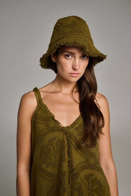 Khaki terry bucket hat with stitched detailing worn by a woman with long brown hair.